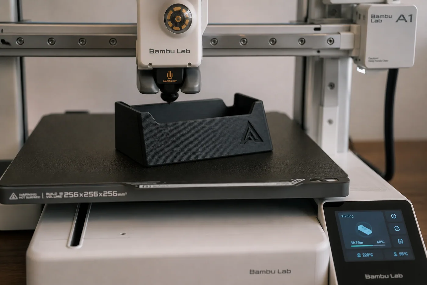 Stampante 3D al lavoro su un porta biglietti nero con il monogramma inciso sul fianco